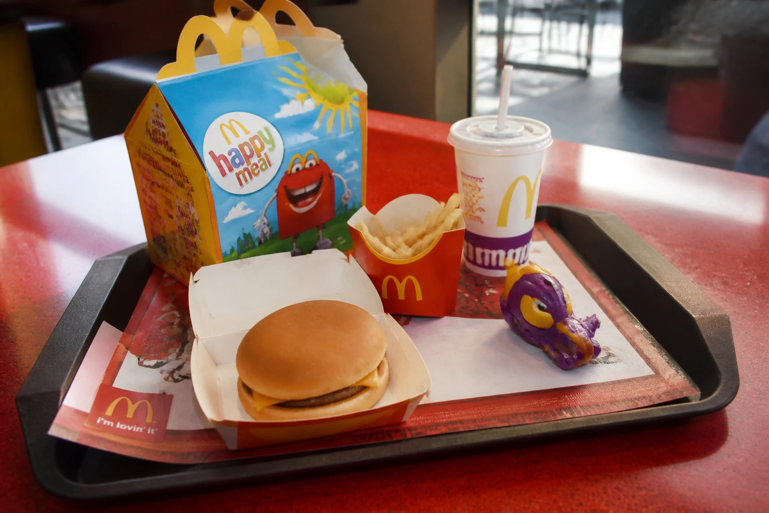 Happy Meal McDonald's posé sur plateau rouge avec hamburger, frites et boisson